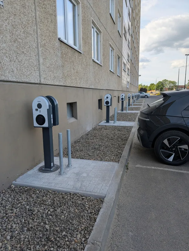Fertige Wallbox-Reihe an einer Wohngebäudefassade mit angeschlossenem Elektrofahrzeug