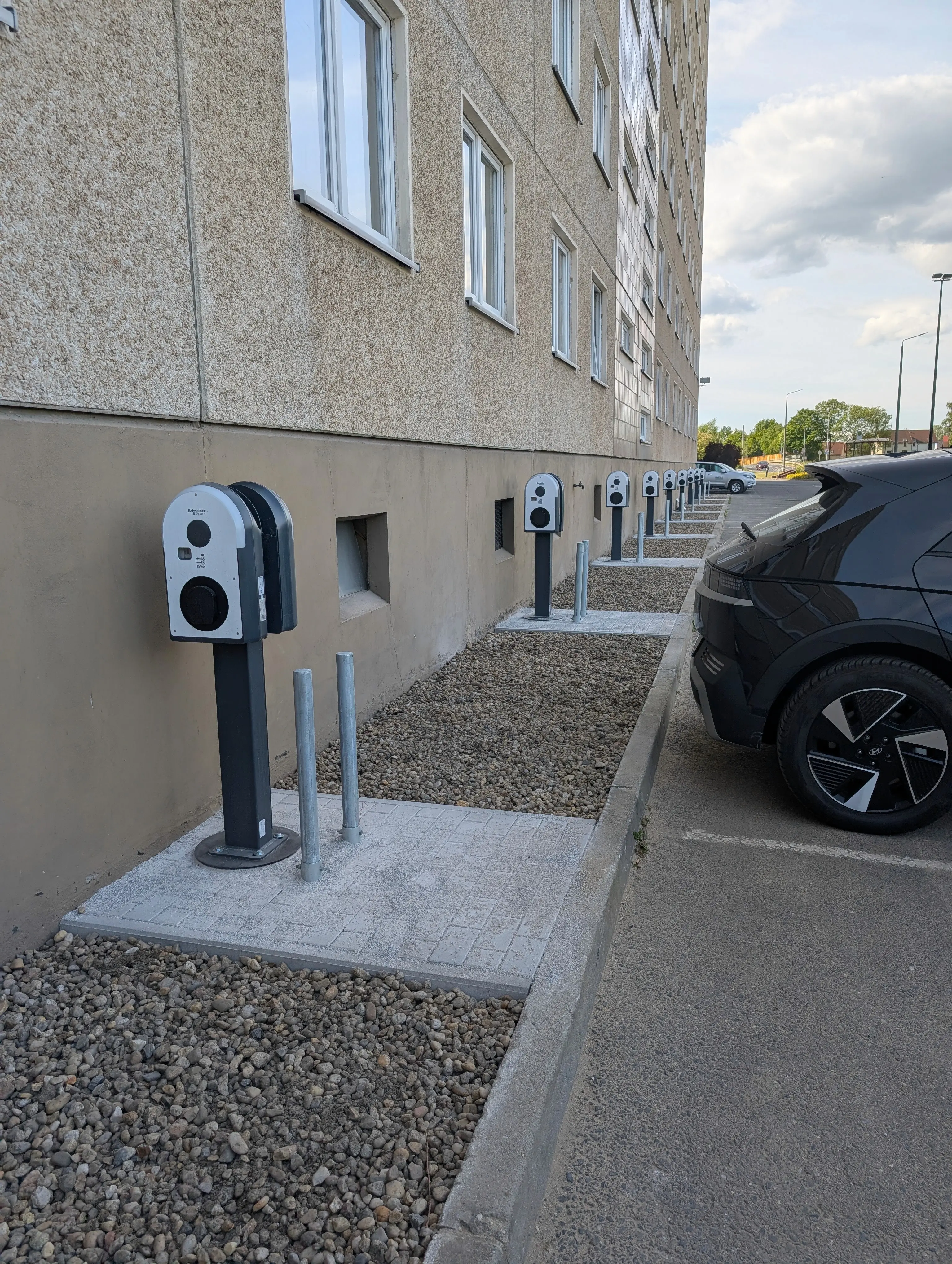 Fertige Wallbox-Reihe an einer Wohngebäudefassade mit angeschlossenem Elektrofahrzeug