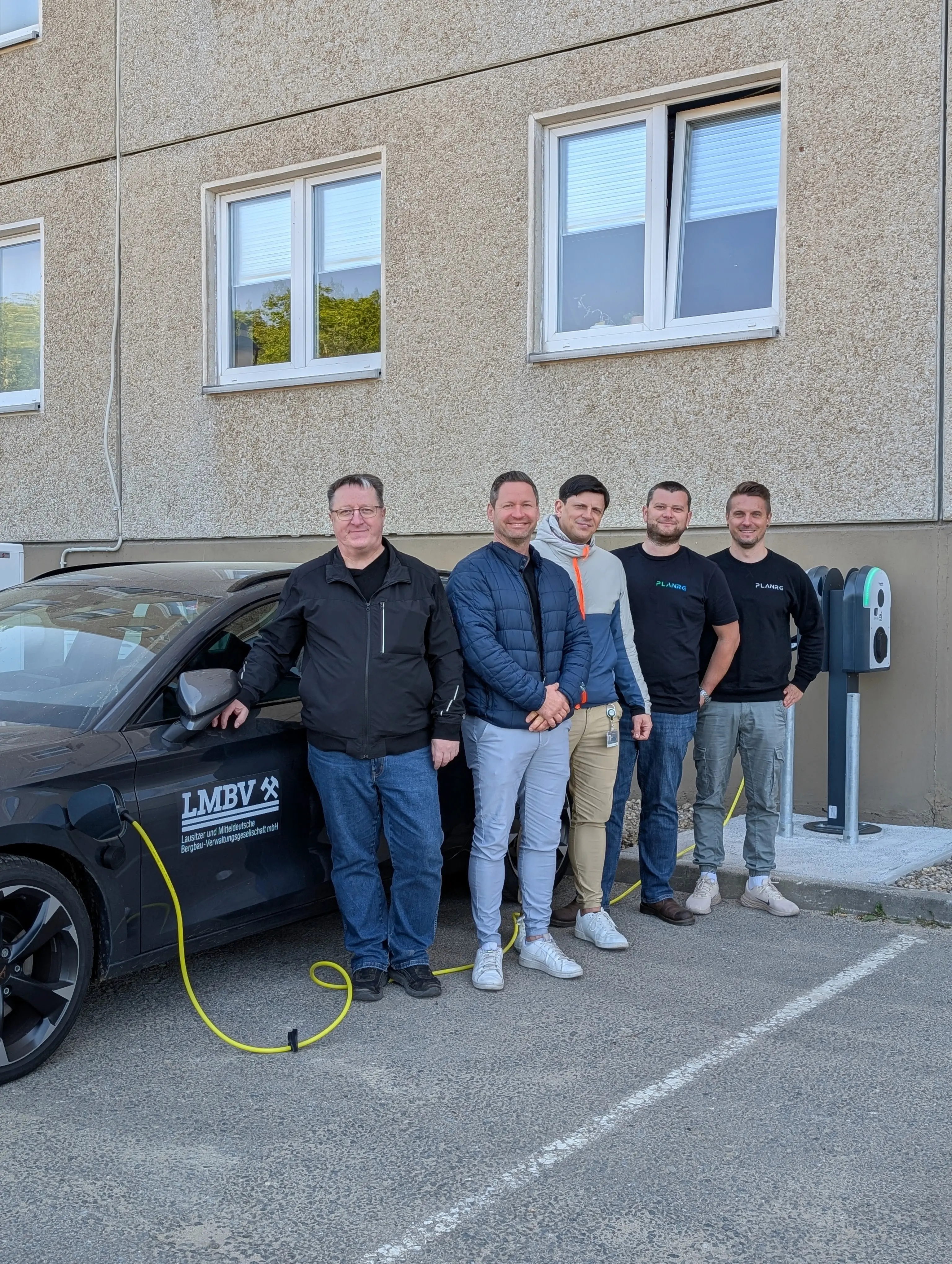 Das PLANRG-Team vor einem ladenden Elektro-Dienstwagen an einer selbst geplanten Ladesäule